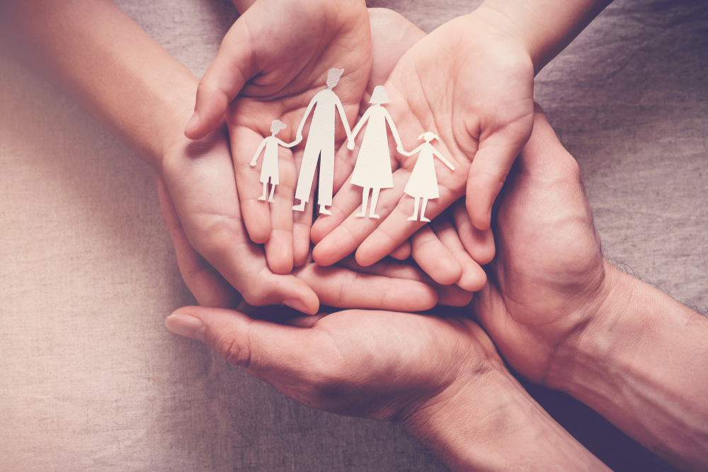 hands holding paper family cutout, family health insurance